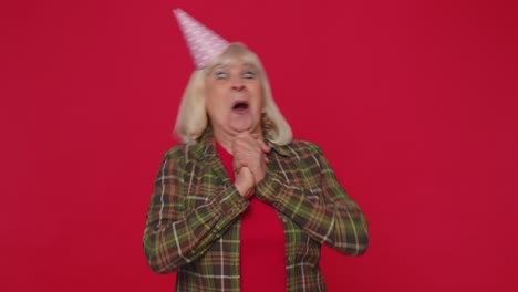 Cheerful-positive-senior-woman-in-cone-festive-hat,-dancing,-having-fun,-celebrating-birthday-party