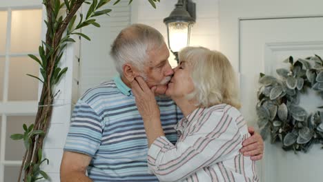Senior-couple-husband-and-wife-embracing-and-making-a-kiss-in-porch-at-home.-Happy-mature-family
