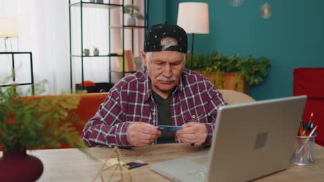Senior-grandfather-man-typing-credit-cards-information-on-laptop,-making-internet-online-shopping