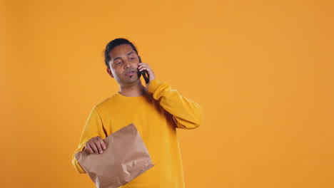 Food-delivery-service-employee-talking-with-customer-on-phone,-studio-background