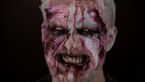 Frightening-man-face-with-Halloween-zombie-bloody-wounded-makeup,-blood-flows-and-drips-on-face