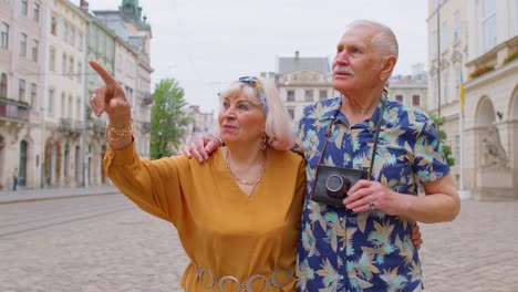 Elderly-old-stylish-family-couple-tourists-man,-woman-on-holidays-vacation-traveling-on-city-street