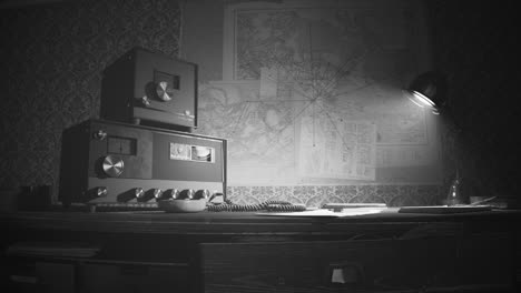 Retro-communication-room-filled-with-dust,-with-old-furniture,-old-fashioned-background-on-the-wall-and-wooden-desk.-Vintage-radio-station-standing-on-the-desk-under-obsolete-lamp