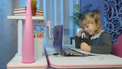 Gelangweiltes-Kind-Hört-Audio-Lektionen,-Lernt-Am-Tisch-Mit-Digitalem-Laptop-Und-Macht-Hausaufgaben
