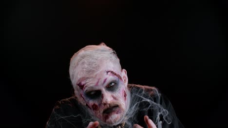 Frightening-man-with-Halloween-zombie-bloody-wounded-makeup,-trying-to-scare,-face-expressions