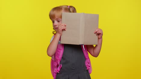 Attractive-teenage-girl-kid-in-school-uniform-wears-pink-backpack-peeping-while-hiding-behind-a-book