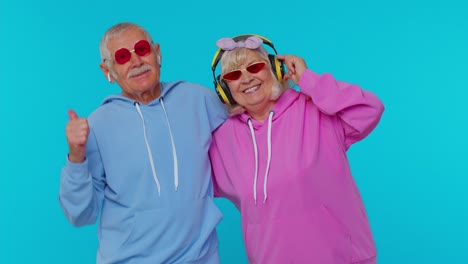 Senior-modern-grandparents-pensioners-listening-music-via-headphones,-dancing-disco-fooling-around