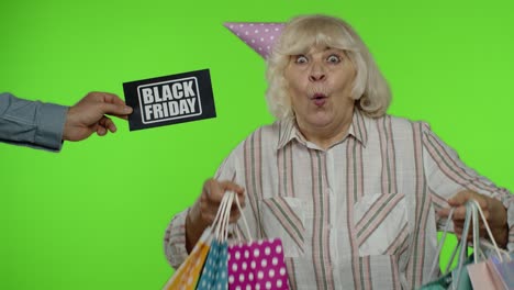 Inscription-advertising-Black-Friday-appears-next-to-joyful-grandmother-with-shopping-bags