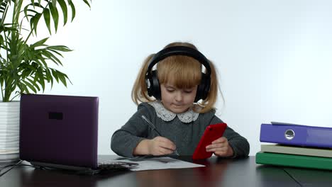 Teen-school-girl-wearing-wireless-headphones-calling-teacher-on-mobile-phone.-Distance-education
