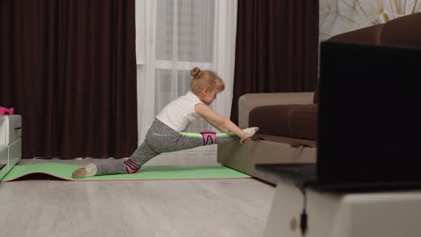 Kleines-Mädchen-Macht-Sportübungen-Und-Sieht-Sich-Zu-Hause-Online-Unterrichtsvideos-Auf-Dem-Laptop-An