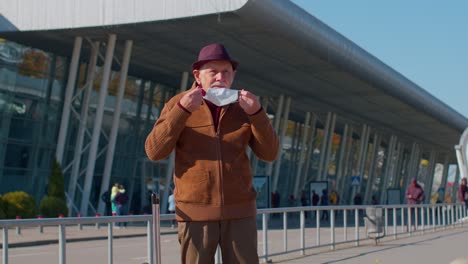 Senior-pensioner-tourist-grandfather-wearing-Protective-Face-Mask,-avoid-coronavirus-near-airport