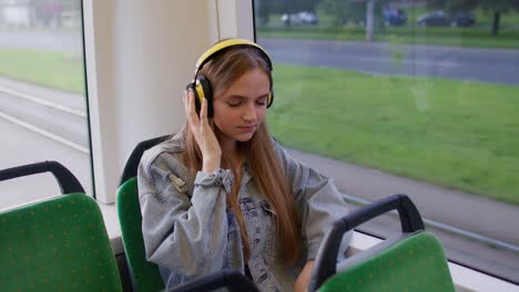 Young-woman-wearing-headphones-listening-music,-funny-relax-dancing-while-traveling-by-bus-to-city
