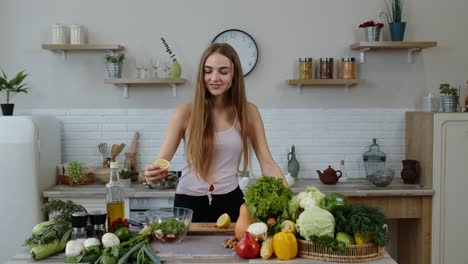 Vegan-girl-in-kitchen-adding-lemon-juice-to-salad-with-raw-vegetables.-Weight-loss-and-diet-concept