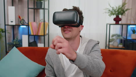Young-man-use-virtual-reality-headset-glasses-at-home-play-3D-video-game-making-gestures-with-hands