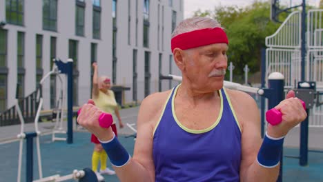 Elderly-senior-man-grandfather-doing-training-weightlifting-exercising-with-dumbbells-on-playground
