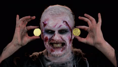 Zombie-man-with-make-up-with-fake-wounds-scars-showing-golden-bitcoins,-mining-btc-cryptocurrency