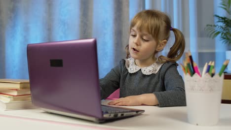 Child-schoolgirl-learning-lessons,-distance-education-at-home-sitting-at-table-using-laptop-computer