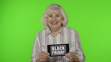 Ältere-Großmutter-Zeigt-Notiz-Mit-Aufschrift-„Black-Friday“,-Lächelt-Und-Sieht-Zufrieden-Mit-Niedrigen-Preisen-Aus
