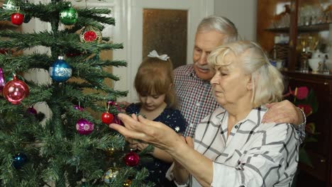 Mädchen-Mit-älterer-Oma-Und-Opa-Schmücken-Künstlichen-Weihnachtsbaum-Mit-Ornamenten-Und-Spielzeug