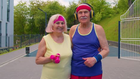 Active-elderly-man,-woman-after-sport-weightlifting-dumbbells-exercises,-smiling-looking-at-camera