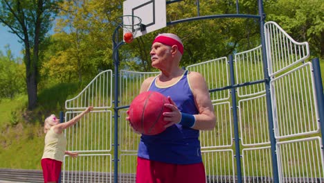 Senior-man-grandfather-athlete-posing-with-ball,-looking-at-camera-on-playground-basketball-court