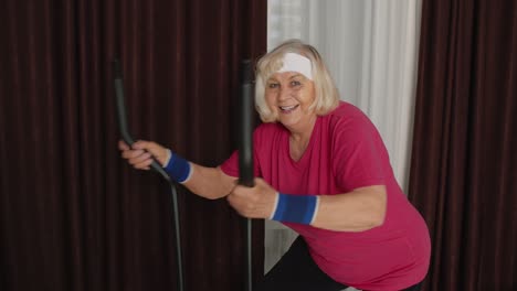 Ältere-Frau-In-Sportkleidung-Mit-Orbitrek-Im-Zimmer-Zu-Hause-Beim-Sporttraining-Mit-Cardio-Übungen