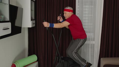 Älterer-Mann-In-Sportkleidung-Benutzt-Orbitrek-Im-Wohnzimmer-Und-Macht-Zu-Hause-Sporttraining-Und-Cardio-Übungen