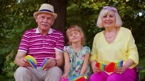 Lächelnde-ältere-Großmutter,-Großvater-Und-Enkelin-Spielen-Ein-Anti-Stress-Spielzeug-Zum-Quetschen