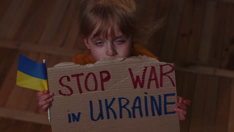 Scared-Ukrainian-girl,-inscription-massage-Stop-War-In-Ukraine-hiding-from-bombing-attack-at-home