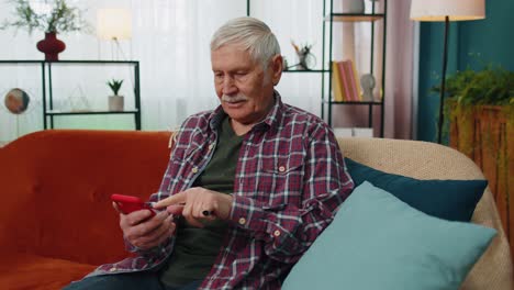 Überglücklicher-älterer-Großvater-Hält-Smartphone-In-Der-Hand,-Aufgeregt-über-Die-Mobile-App-Für-Sportwetten,-Bei-Der-Er-Zu-Hause-Gewinnt