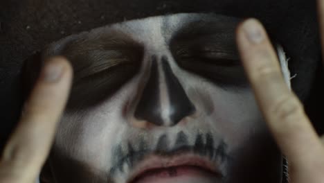 Close-up-man-face-in-skeleton-Halloween-cosplay-removing-hands-from-face-and-looking-wide-open-eyes