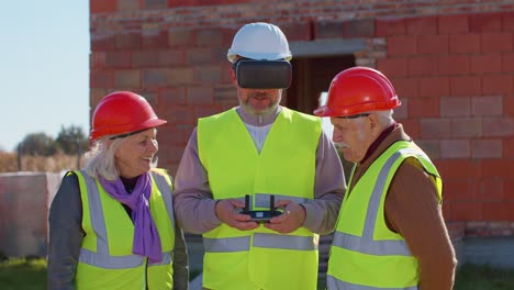 Specialist-worker-fly-on-drone-on-building-construction-site,-showing-house-to-grandparents-clients