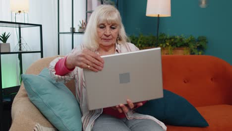 Senior-old-grandparent-starts-working-on-laptop,-sends-messages,-makes-online-purchases-at-home