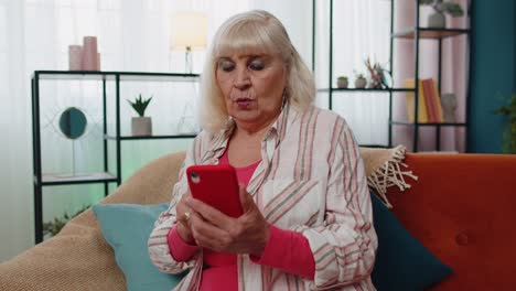 Erstaunte-ältere-Großmutter-Nutzt-Mobiles-Smartphone,-Erhält-Gute-Nachrichten,-Schockiert-über-Plötzlichen-Sieg