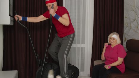 Senior-mature-grandfather-and-grandmother-using-orbitrek,-doing-weight-lifting-dumbbells-exercises