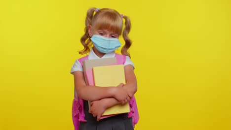 Unhealthy-little-schoolgirl-kid-wearing-protective-medical-mask,-standing-with-books-looking-tired