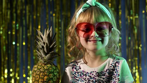 Trendy-stylish-child-kid-with-pineapple-fruit-drinking-juice-in-futuristic-club-with-neon-light