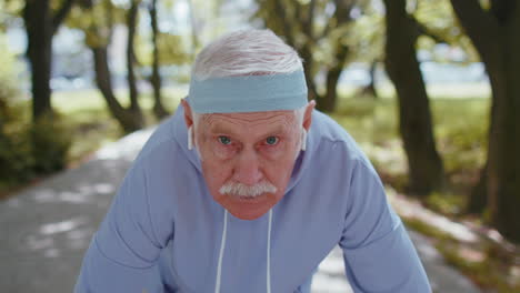 Senior-athletic-man-grandfather-running-jogging-in-sunny-park-during-morning-workout-cardio-outdoors