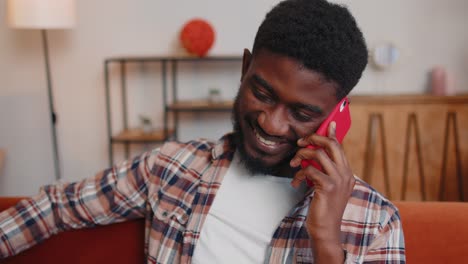 Young-adult-african-american-man-enjoying-talking-mobile-phone-conversation-with-friends-at-home