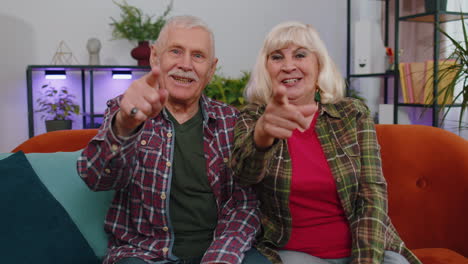 Senior-family-grandparents-man-woman-smiling-excitedly-and-pointing-to-camera,-choosing-lucky-winner
