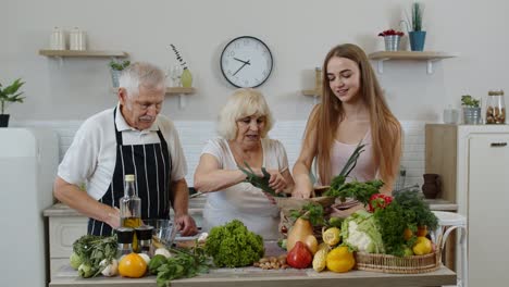 Senior-couple-in-kitchen-receiving-vegetables-from-granddaughter.-Healthy-raw-food-nutrition