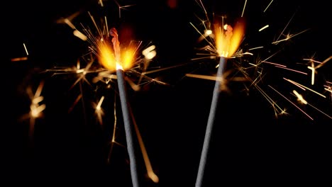 Bengal-fires,-New-Year-sparkler-candles,-sparkling-lights-burning-on-a-black-background,-slow-motion