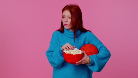 Redhead-young-woman-basketball-fan-eating-popcorn-doing-winner-gesture,-celebrating-victory-win