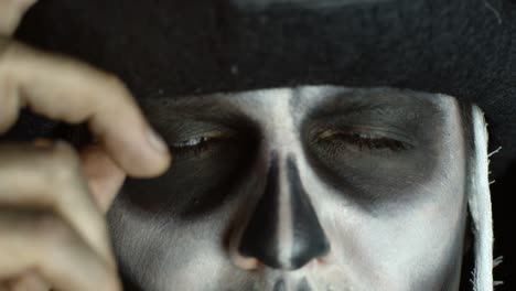 Close-up-of-scary-man-face-in-carnival-skull-Halloween-makeup-of-skeleton-looking-creepy-at-camera