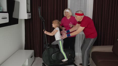 Active-old-senior-grandfather,-grandmother-training-kid-granddaughter-how-to-using-orbitrek-at-home