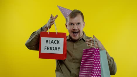 Smiling-man-showing-Black-Friday-inscription-on-shopping-bags,-celebrating,-rejoicing-good-discounts