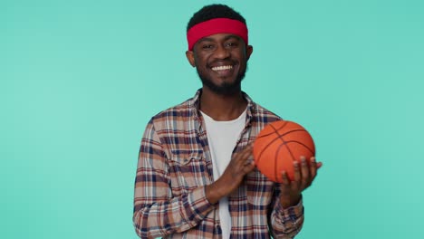 Barbudo-Sonriente-Joven-Afroamericano-Aficionado-Al-Deporte-De-Baloncesto-Sosteniendo-La-Pelota-Mirando-A-La-Cámara