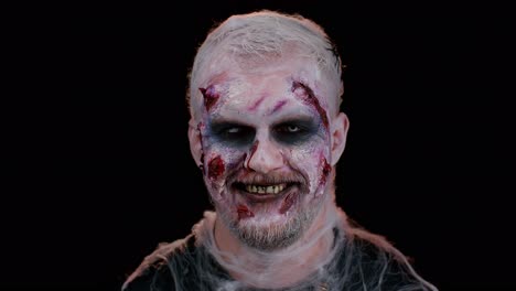 Playful-sinister-man-Halloween-crazy-zombie-with-bloody-wounded-scars-face-blinking-eye-toothy-smile