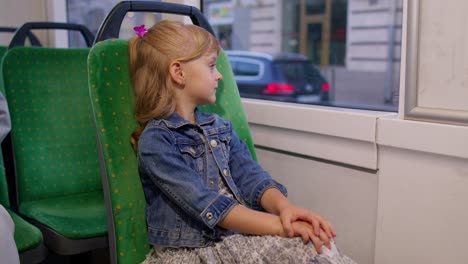 Portrait-of-child-girl-passenger-riding-at-public-modern-bus-or-tram-transport,-looking-out-window