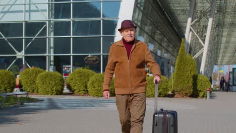 Senior-Pensionista-Abuelo-Turista-Empresario-Caminando-Desde-La-Puerta-Del-Aeropuerto-Con-Bolsa-De-Equipaje